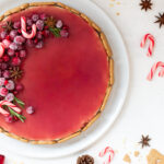 Spekulatius Cheesecake mit einem Granatapfelspiegel und einem opulenten Fruchttopping aus kandierten Cranberries, Granatapfelkernen, Sternanis und Rosmarin, von oben fotografiert
